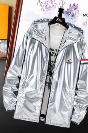 metallic windbreaker jacket with a hood, tricolor sleeve stripes, and a black circular logo patch hanging on a wooden hanger.