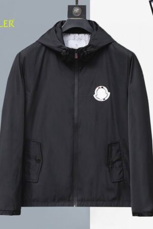 Classic black lightweight hooded jacket with a white circular logo patch on the chest, hanging on a designer hanger.