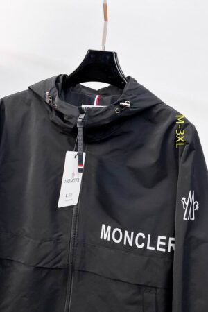 Black Moncler lightweight zip-up windbreaker with a hood and signature logo patch on the left sleeve, displayed on a minimalist background.