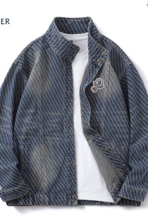 Moncler-style blue denim jacket with diagonal white stripes, a stand collar, and gold-tone snap-button closures over a central zipper. Features a circular logo patch on the chest.
