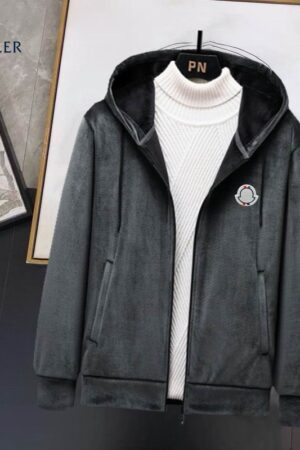 zip-up hooded jacket made of a soft fleece or velour material, featuring a white turtleneck underneath and a small circular black and white logo patch on the left chest.