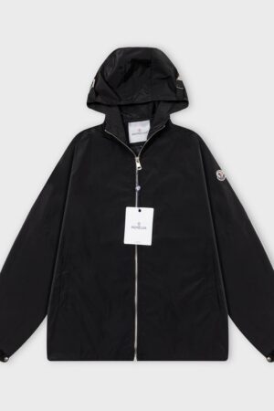 Black Moncler lightweight zip-up windbreaker with a hood and signature logo patch on the left sleeve, displayed on a grey background.