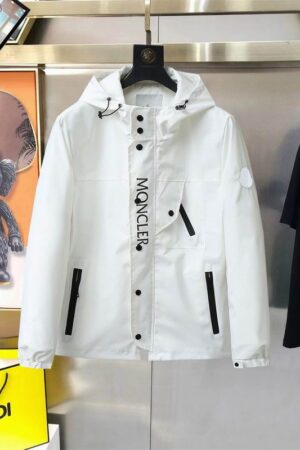 Close-up of the crisp white performance fabric and the bold "MONCLER" typography on the front placket of a premium utility jacket.