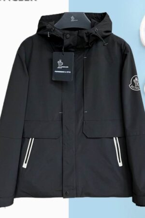 Men's black technical parka with white zipper piping, an oversized sleeve logo, and a structured hood.