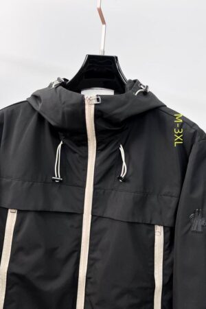 Black Moncler Grimm hooded windbreaker featuring cream-colored zippers, a drawstring hood, and a signature logo patch on the left sleeve