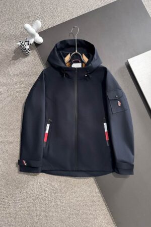 A high-quality navy blue hooded windbreaker jacket featuring a sleeve logo patch and red, white, and blue zipper accents on a neutral background.