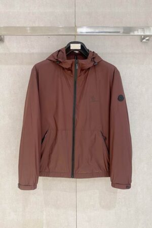 Front-facing photo of a Moncler Vanoise hooded windbreaker in a brownish-orange color with black zipper and logo detail on the sleeve.