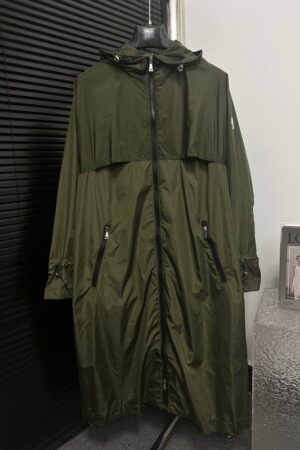 Full-length view of the Moncler Malavoy long parka in olive green, featuring a hooded design, black zippers, and the iconic sleeve logo patch.