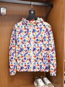 A vibrant, multi-colored men's windbreaker featuring an abstract graffiti print in orange, blue, and white, hanging in a wooden wardrobe.