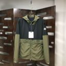 Two hooded Moncler style block-color jackets: one with a black upper half and olive green lower half, and one in solid black. Both feature a white patch logo and "MON CLER" lettering across the chest.