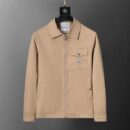 A front-facing view of a beige men's zip-up jacket with a pointed collar, a chest flap pocket, and a logo patch, hanging against a grey gradient background