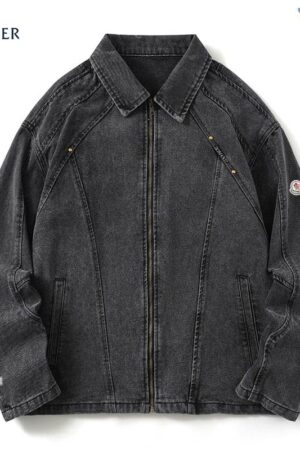 Moncler-style washed black denim jacket with a front zip closure, a classic collar, and angled chest seams with metal stud details. A small logo patch is visible on the left sleeve.