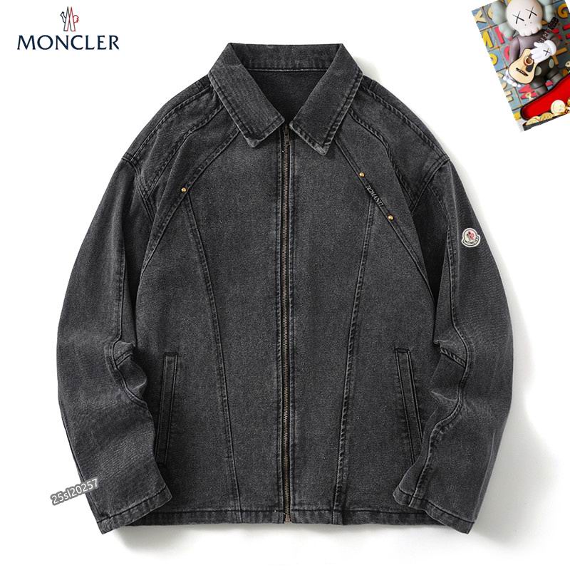 Moncler-style washed black denim jacket with a front zip closure, a classic collar, and angled chest seams with metal stud details. A small logo patch is visible on the left sleeve.