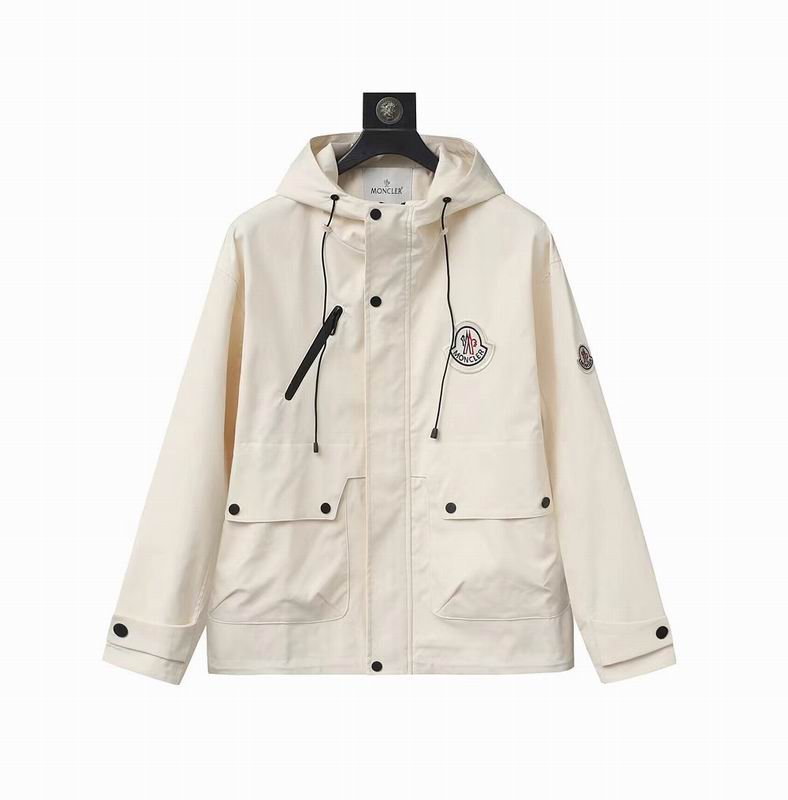 A cream-colored premium utility field jacket with two large front cargo pockets, a vertical chest zipper, and a signature logo patch on the chest.