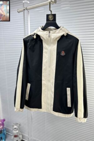 Close-up of the cream-colored sleeve detailing and the circular signature logo patch on the chest of a premium sport shell.