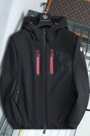 A high-performance black shell jacket featuring dual red-trimmed chest zippers and an integrated protective hood.