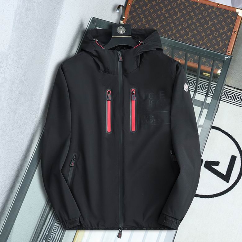 A high-performance black shell jacket featuring dual red-trimmed chest zippers and an integrated protective hood.
